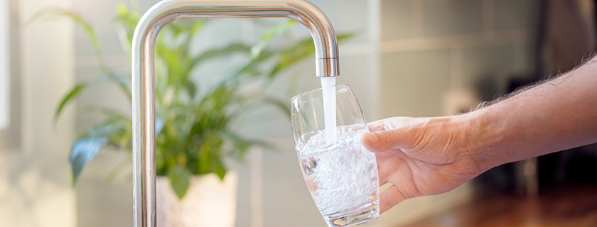 Quelqu'un remplissant un verre d'eau à partir de l'évier de la cuisine.