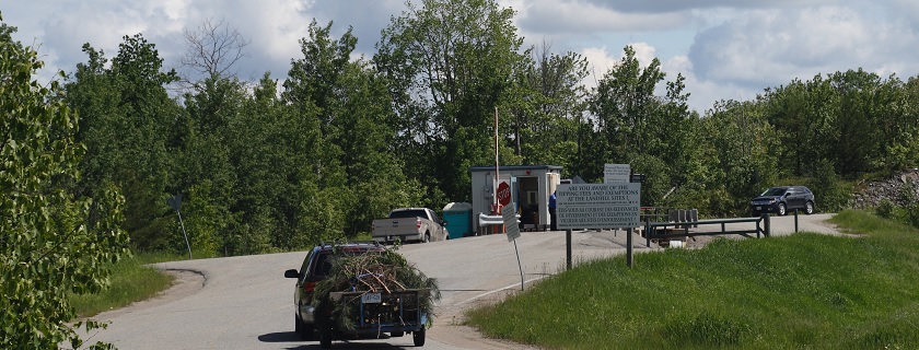 Une fourgonnette tirant une remorque remplie d'arbustes en direction d'un site d'enfouissement.